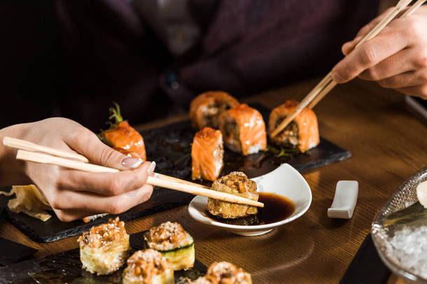 人们在餐厅用筷子吃寿司的裁剪景观