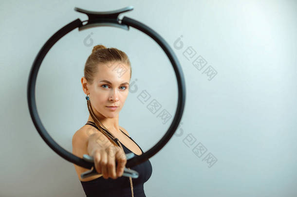 健康女人拿着健身戒指，灰色背景。复制空间，运动横幅，美丽的身体.