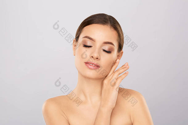 美丽的女人的肖像与自然化妆触摸她的脸。美丽的年轻女子与新鲜干净完美的皮肤。皮肤护理的概念。美容, 美容和水疗。面部护理。天然肌肤.