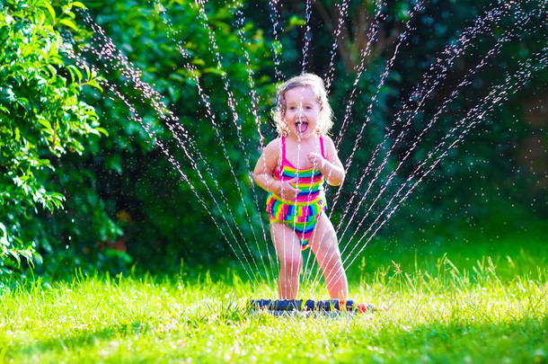 小女孩玩花园喷水