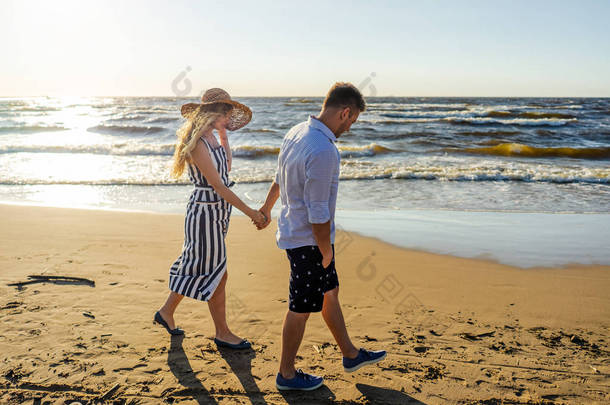 年轻夫妇在爱牵手的侧面视图在里加的沙滩上散步, 拉脱维亚