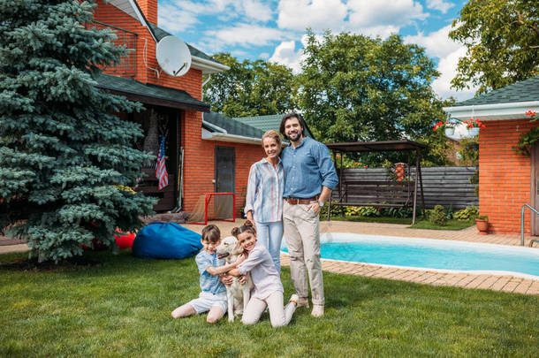 欢快的家庭与拉布拉多狗看相机, 而花<strong>时间</strong>在后院的乡间别墅在夏天的一天