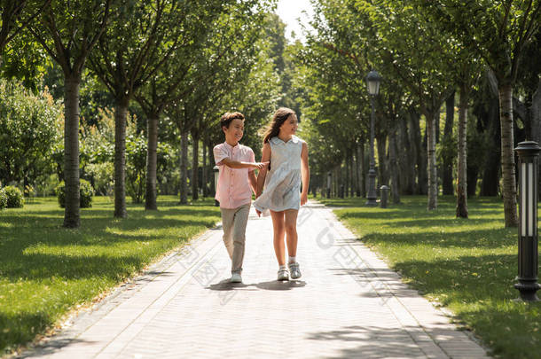 你是我最好的朋友。小男孩和女孩手牵手，微笑着一起走在公园