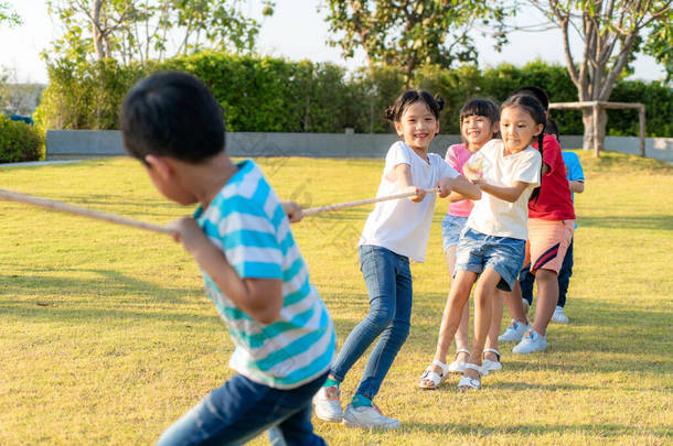 一群快乐的亚洲小孩在夏天的公园操场上玩拔河或拉绳<strong>游戏</strong>。儿童与<strong>娱乐</strong>概念