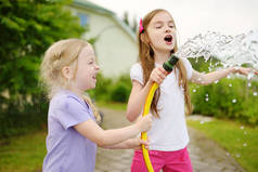 可爱的小女孩在温暖的夏日里玩着花园软管。儿童户外活动.