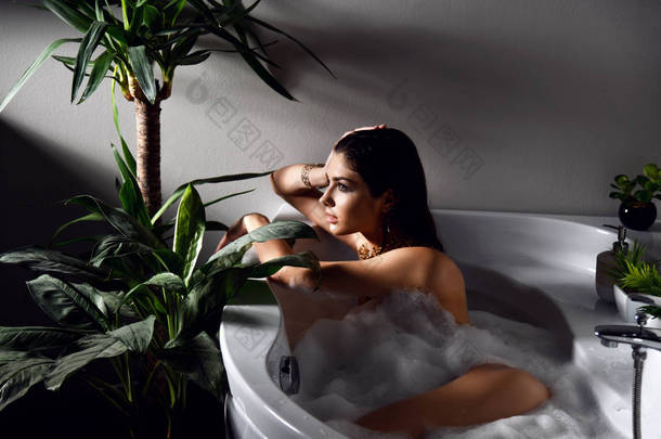 年轻美丽的女人躺在浴缸里洗澡 
