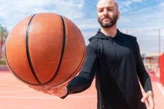 有吸引力的人拿着篮球的特写。球位于焦点和前景上.