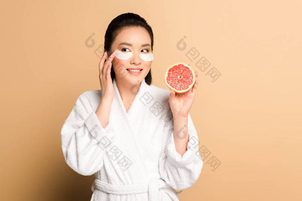 穿着浴衣的美丽的亚洲女人，脸上带着眼斑，脸上带着淡褐色背景的柚子