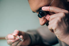 乳胶指尖钟表匠手持眼镜百叶窗和手表零件的侧视图 