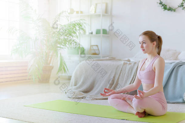 运动年轻女孩，女人在家里练习室内瑜伽。阿萨纳瑜伽，健康理念，我心中的瑜伽