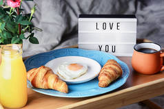 面包，咖啡和煎蛋，早餐在床上。 给你爱的人一个浪漫的早晨 有题词的光盒爱你
