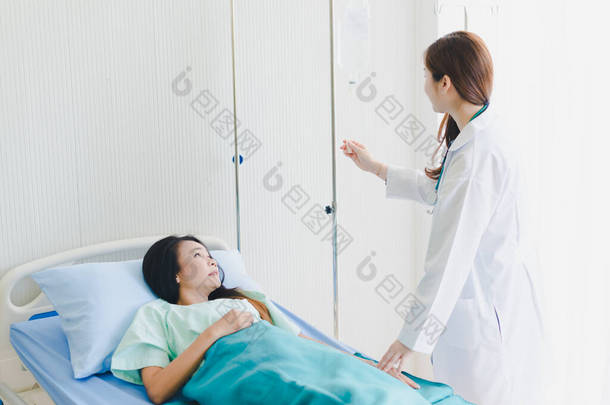 亚洲女医生探访躺在病床上的病人.