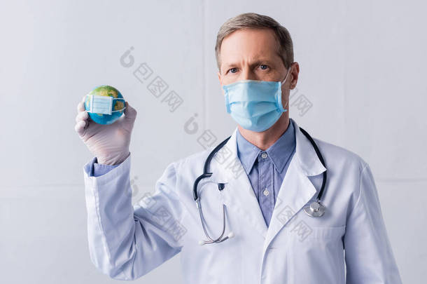 头戴乳胶手套，头戴医用面罩，头戴灰色小球的成熟医生