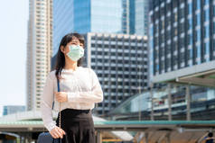 身穿白衬衫的年轻紧张的亚洲女商人将在污染城市工作，她戴着防污染面罩，防止PM2.5灰尘、烟雾、空气污染和COVID-19 。.