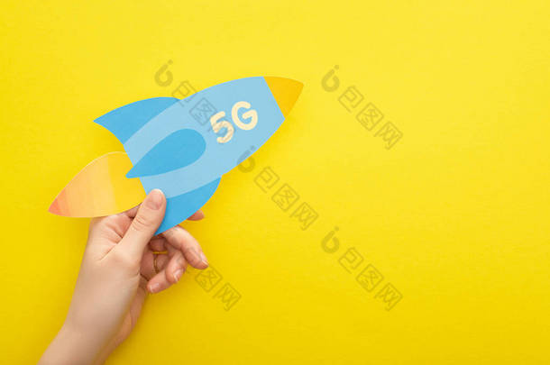 黄色背景上印有5g字母的妇女手持纸制火箭的剪影