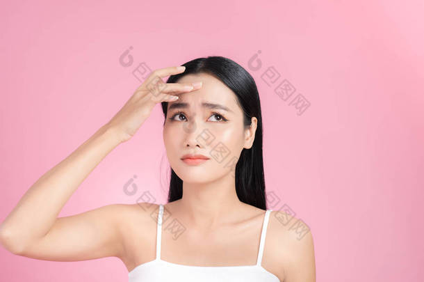 年轻的亚洲女人摸着她的脸，担心她的脸。 粉刺、粉刺、清洁、油腻、干燥的皮肤概念. 