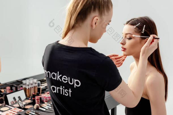 穿着黑色T<strong>恤</strong>的女人，化妆艺术家字体，在模特身上涂上眼影 