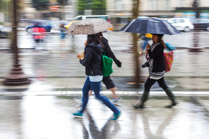 年轻人在运动模糊走在多雨的城市 走路看手机