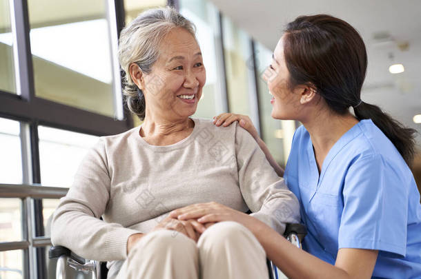 <strong>养老院</strong>的友好护理人员在走廊里与亚洲老年妇女交谈