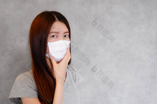 在灰色背景下戴着保护面具的亚洲女人的近照。人们戴外科口罩是<strong>因为</strong>pm2.5空气污染、病毒流感、头孢病毒和COVID-19<strong>热</strong>。保健的概念.
