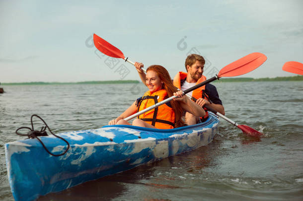 一对快乐的夫妇在河里<strong>划船</strong>，背景是日落
