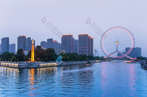 天津是中国北方沿海的大都市，<strong>高大</strong>的巨型摩天轮建在永乐桥上，在天津的海河上. 