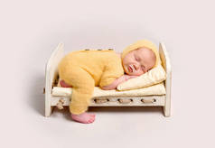 婴儿穿着针织黄色服装睡在婴儿床上
