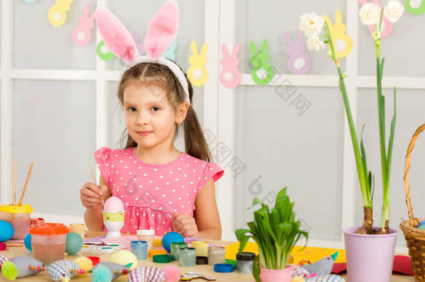 小女孩与复活节兔子耳朵画复活节彩蛋在家里.