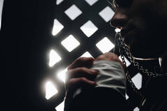 天主教牧师在黑暗中与光芒相映成趣地亲吻他项链上的十字架的剪影