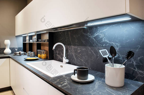 大理石效果厨房柜台与器具和白色矩形水槽下面墙壁安装橱柜和飞溅回