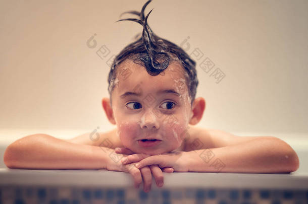 欢快的男孩与湿头发看着<strong>远离</strong>在浴缸