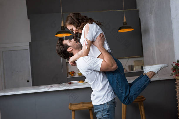 英俊的男人抱在怀里有吸引力的女朋友在现代厨房 
