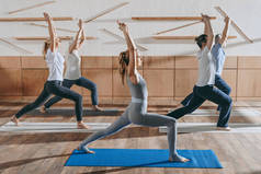 在工作室的垫子上练习瑜伽与教练的高级人员组