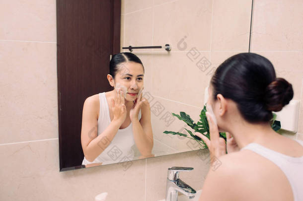 亚洲女人用泡沫清洁面部肌肤让自己快乐.