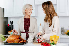 有吸引力的成人女儿和资深母亲一起烹调感恩节晚餐