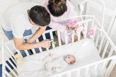 年轻父母在家里看婴儿床的高角度的看法