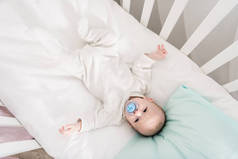头顶上的小婴儿与奶嘴躺在婴儿床