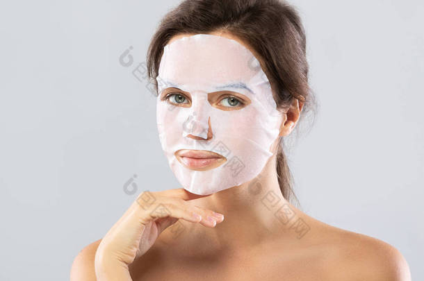 妇女与床单保湿面膜在她的脸上隔离在格拉