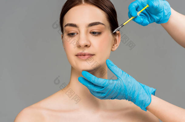 <strong>整形</strong>外科医生的裁剪视图使美容注射妇女隔离在灰色 