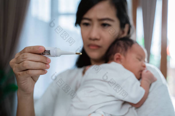 亚洲母亲使用温度计担心他们的孩子的健康