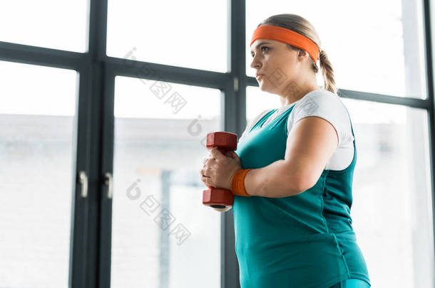 自信超重的女孩拿着哑铃在健身房