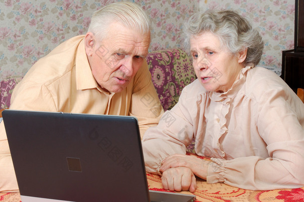 老夫妇看起来到笔记本电脑与积极关注