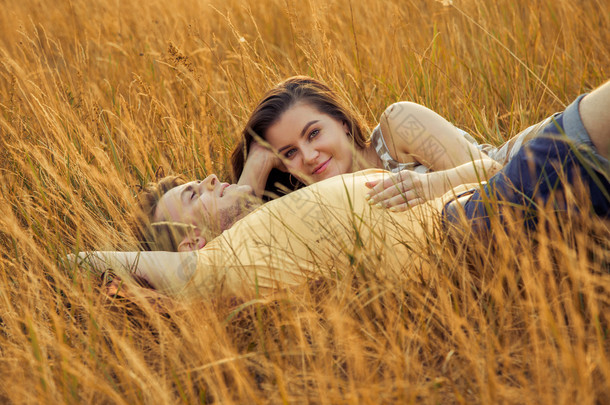 爱的情侣躺在秋季公园的花卉领域。享受, 放松和 r