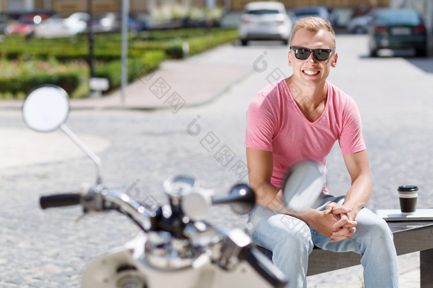 坐在摩托车旁喝咖啡的帅哥