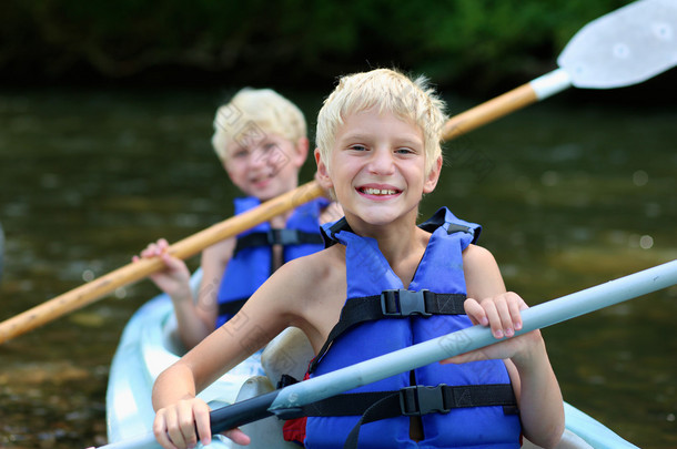 皮划艇在河上的两个快乐的学校男孩