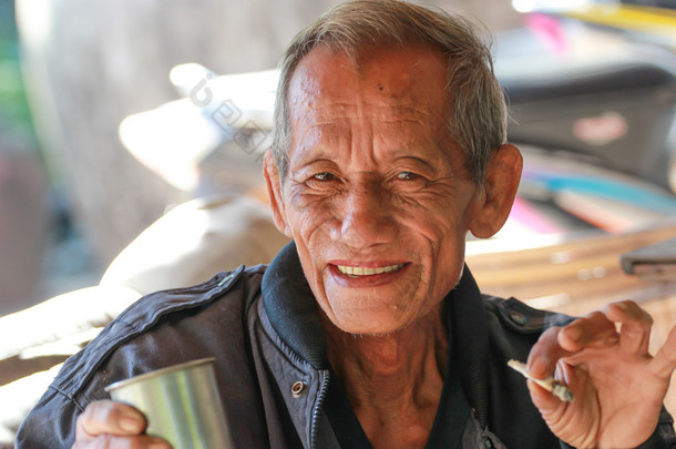 老年的快乐老人捧着一杯咖啡
