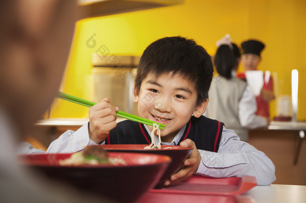 学校的男孩在学校的食堂吃面条