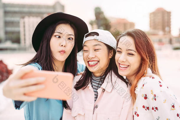 快乐的亚洲女孩在户外用手机自私自利- -年轻有趣的社交朋友，利用新的流行技术- -人、千年一代和年轻人的生活方式观念