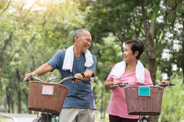快乐的亚洲老年夫妇，穿着蓝色和粉色衬衫，笑着 