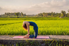 在巴厘岛的健康撤退期间, 年轻女子练习瑜伽户外在稻田里的早晨